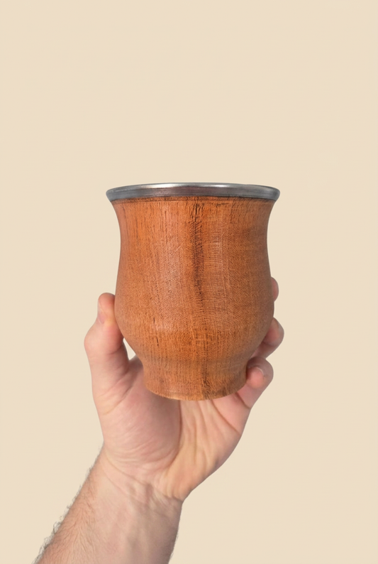 Mate Camionero de Algarrobo frontal sostenido en una mano sobre fondo beige