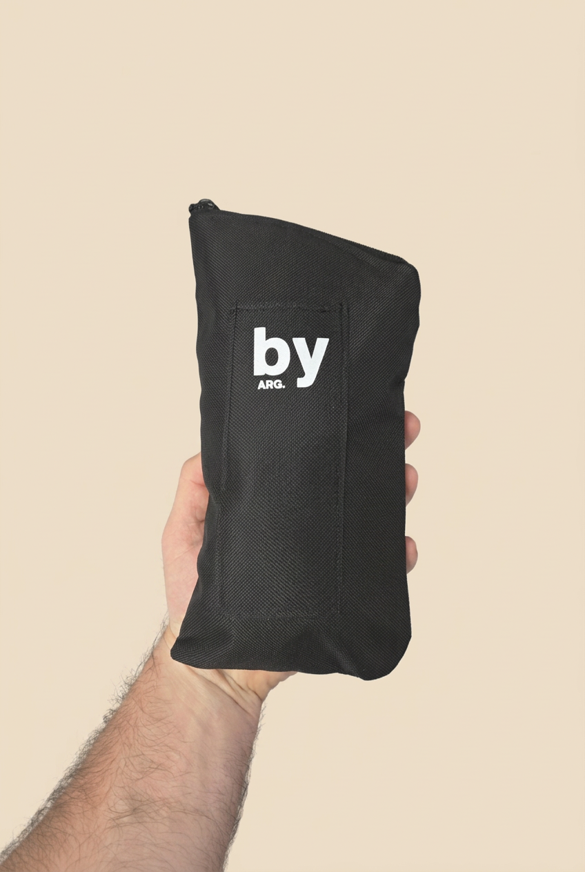 Yerbero ByArg negro sostenido en una mano sobre fondo beige sin sombras