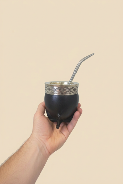 Bombilla Pico de Loro en un mate negro sostenido en una mano sobre fondo beige